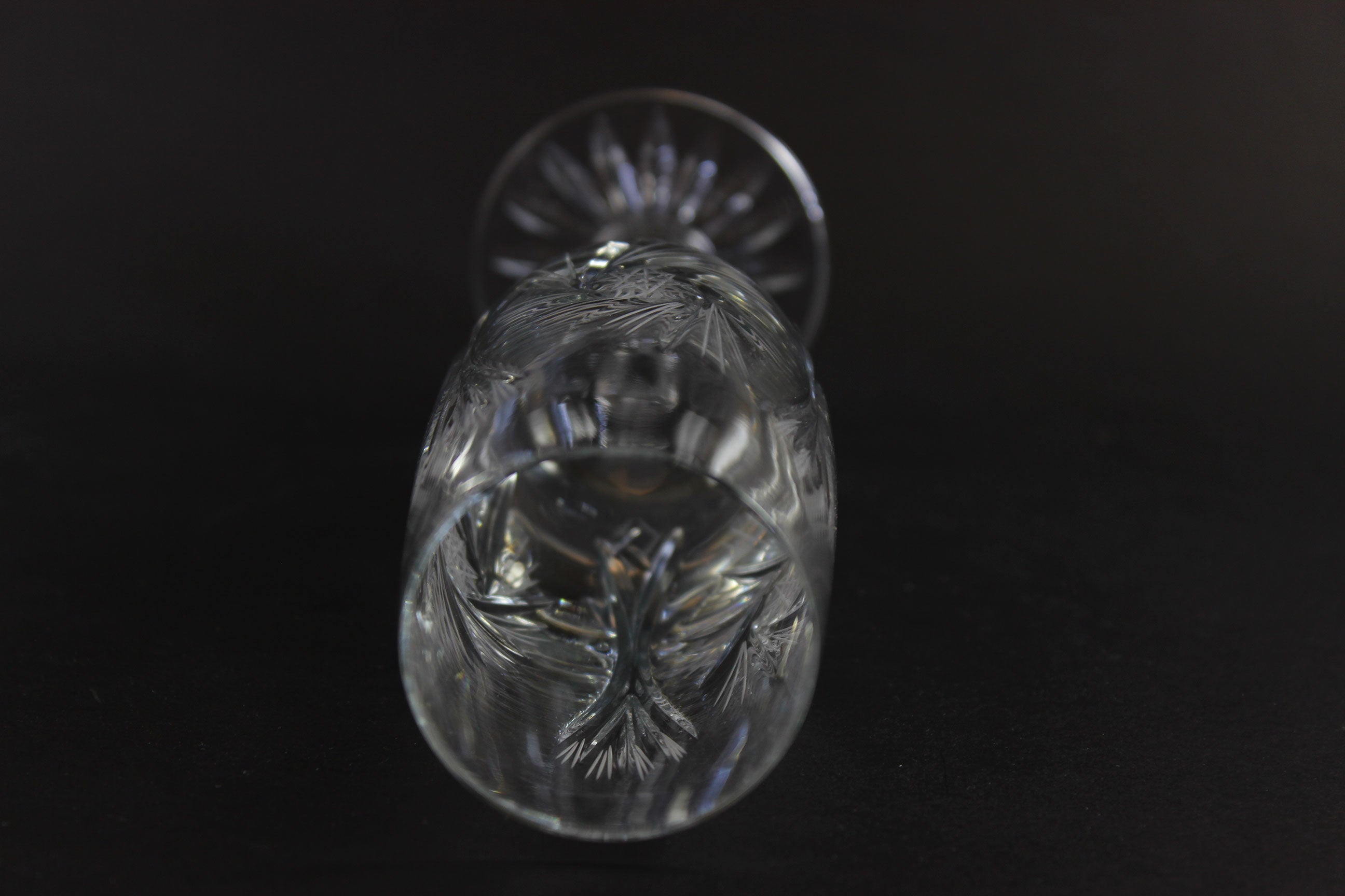 Two crystal champagne flutes with cut pinwheel design on a black background