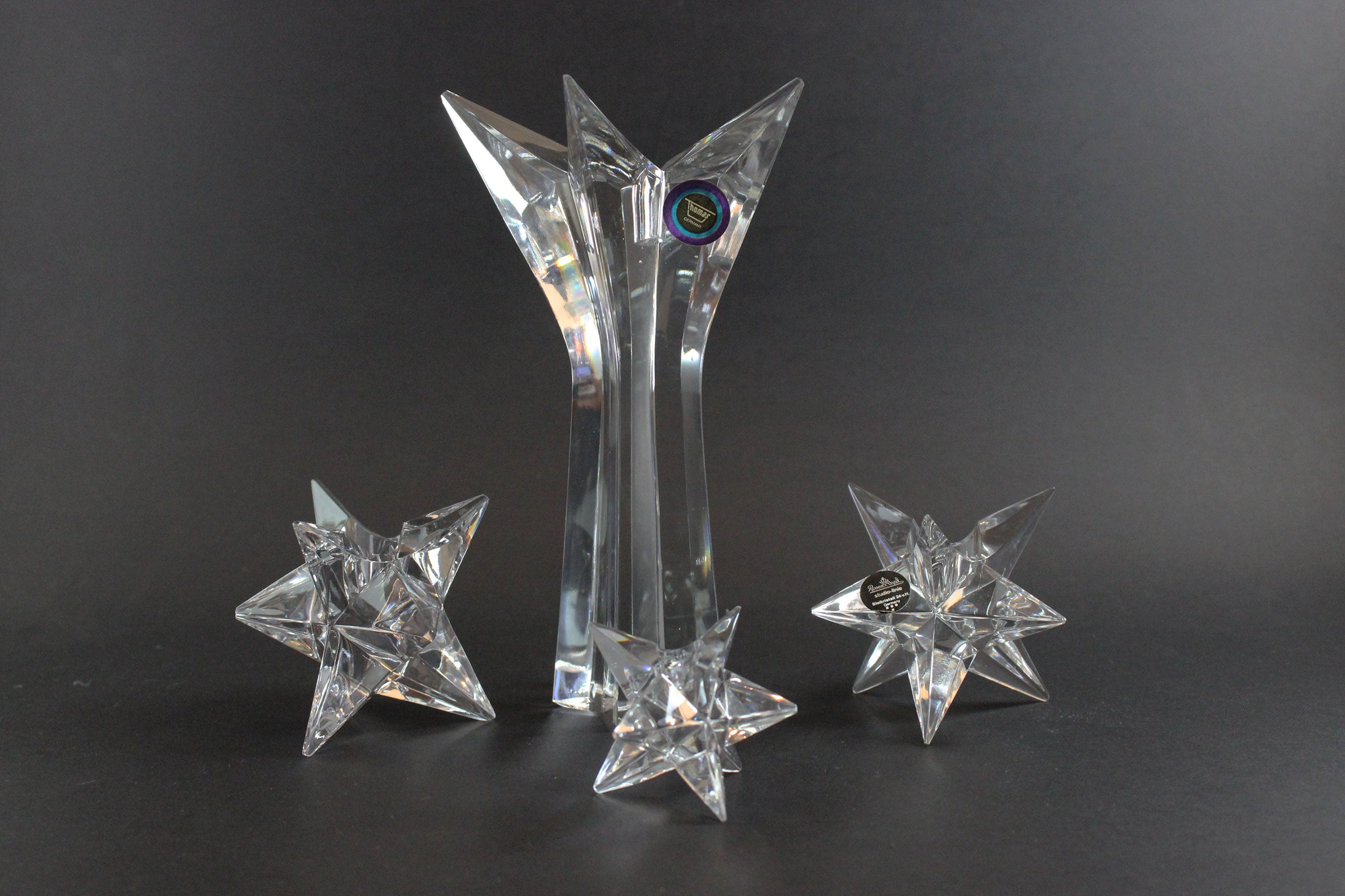 Set of crystal star-shaped candleholders on a dark background
