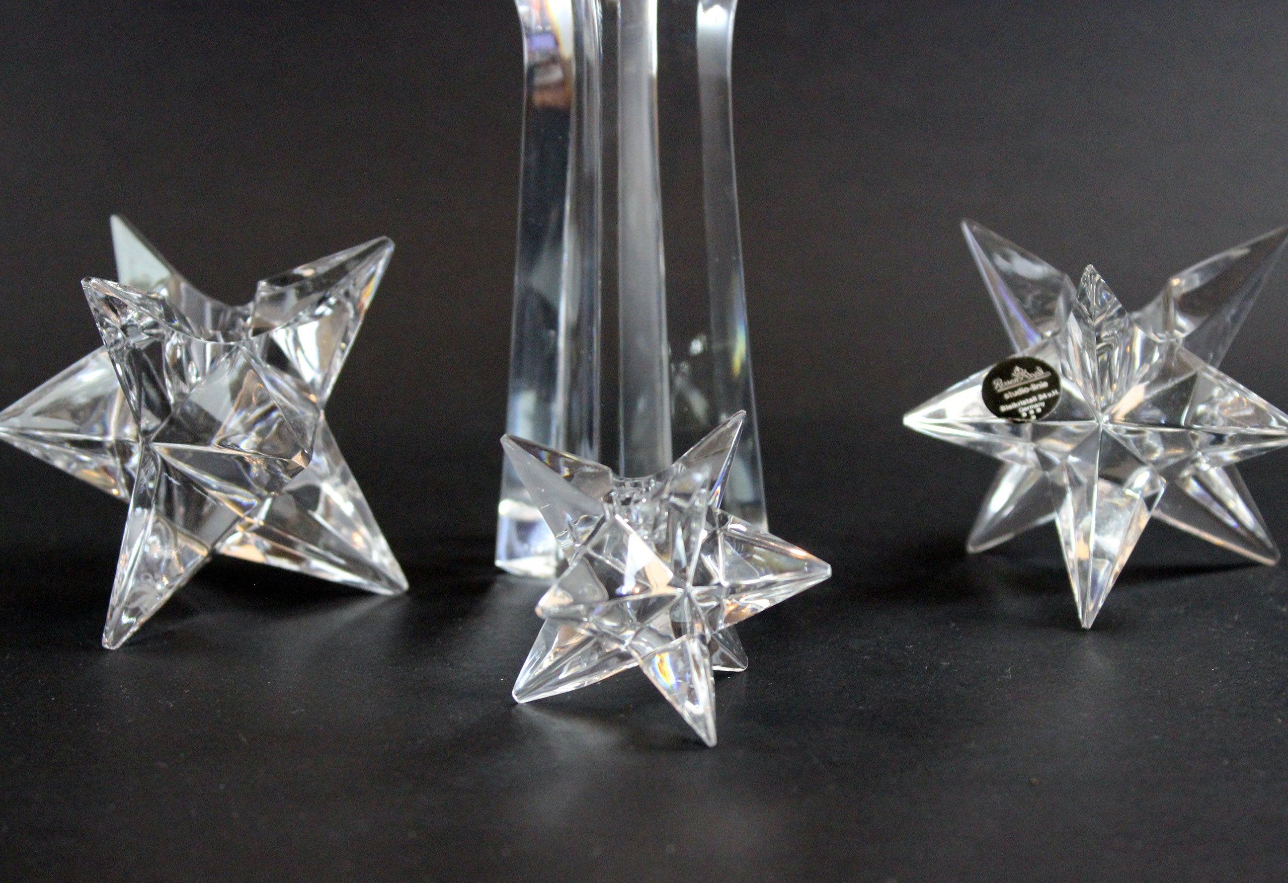 Set of crystal star-shaped candleholders on a dark background