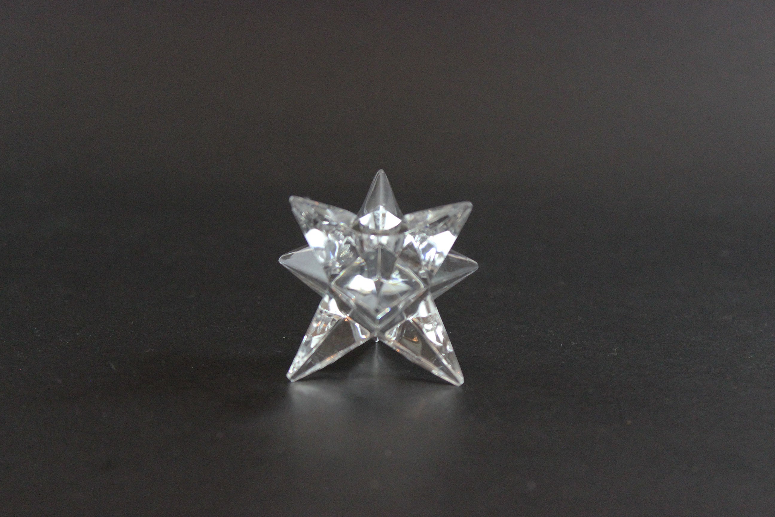 Set of crystal star-shaped candleholders on a dark background