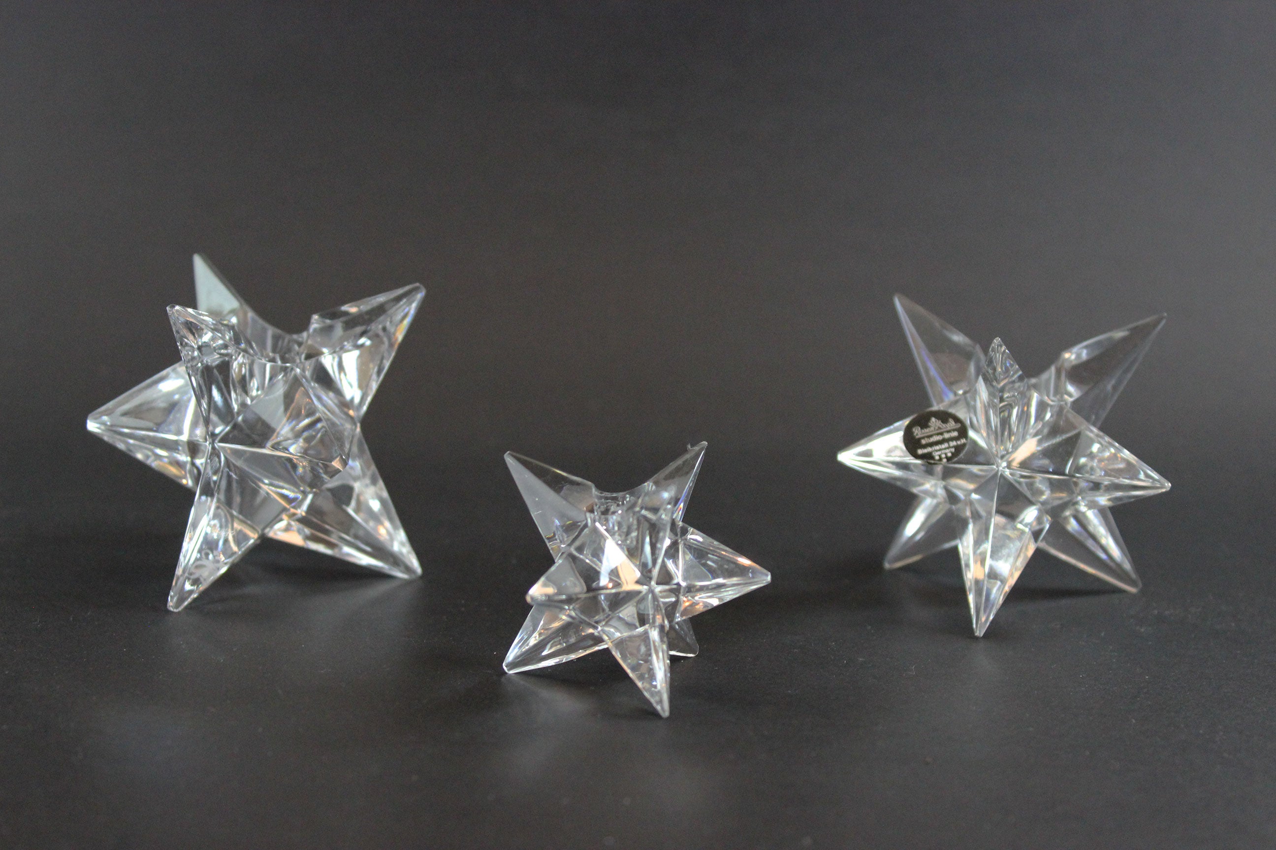 Set of crystal star-shaped candleholders on a dark background