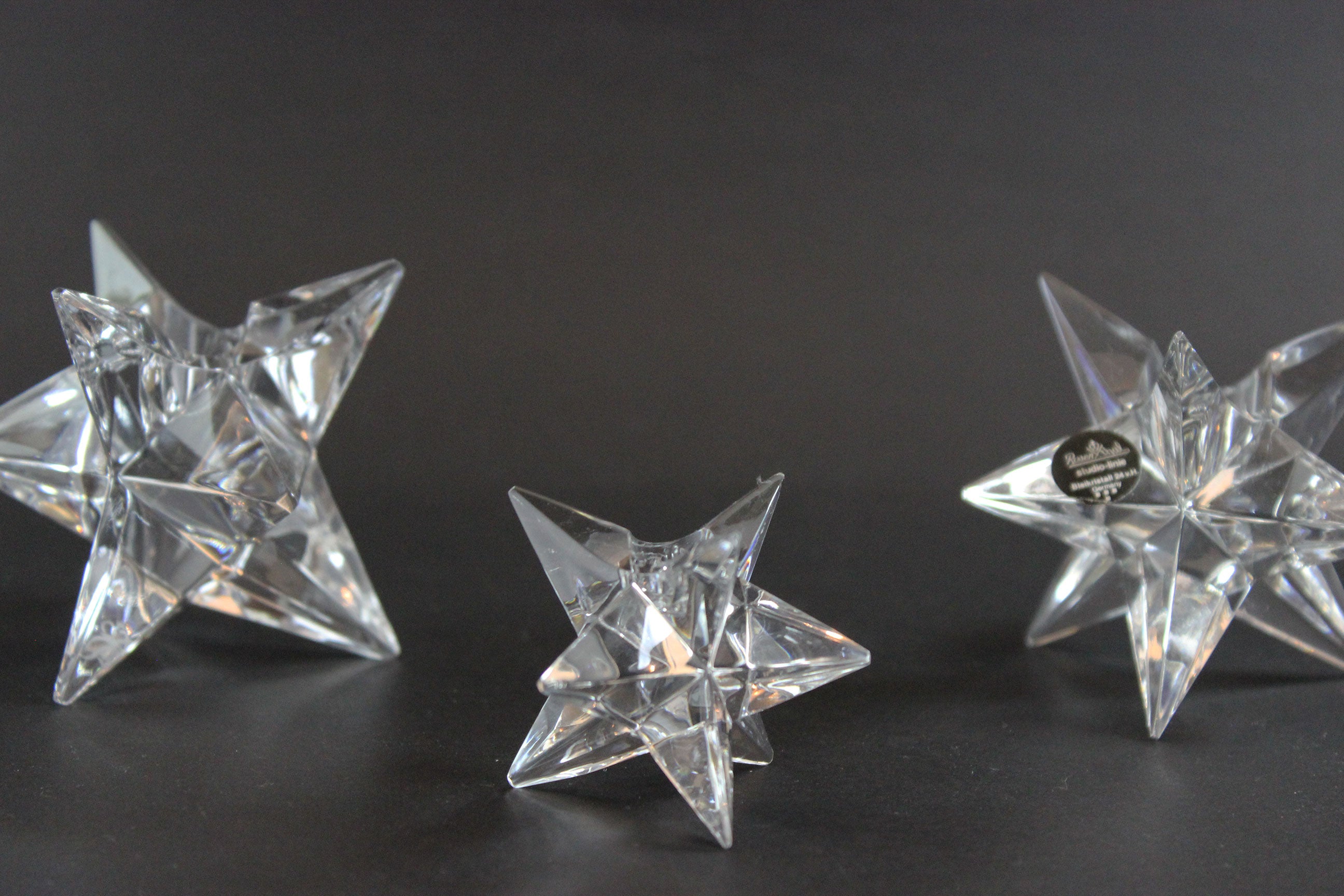 Set of crystal star-shaped candleholders on a dark background