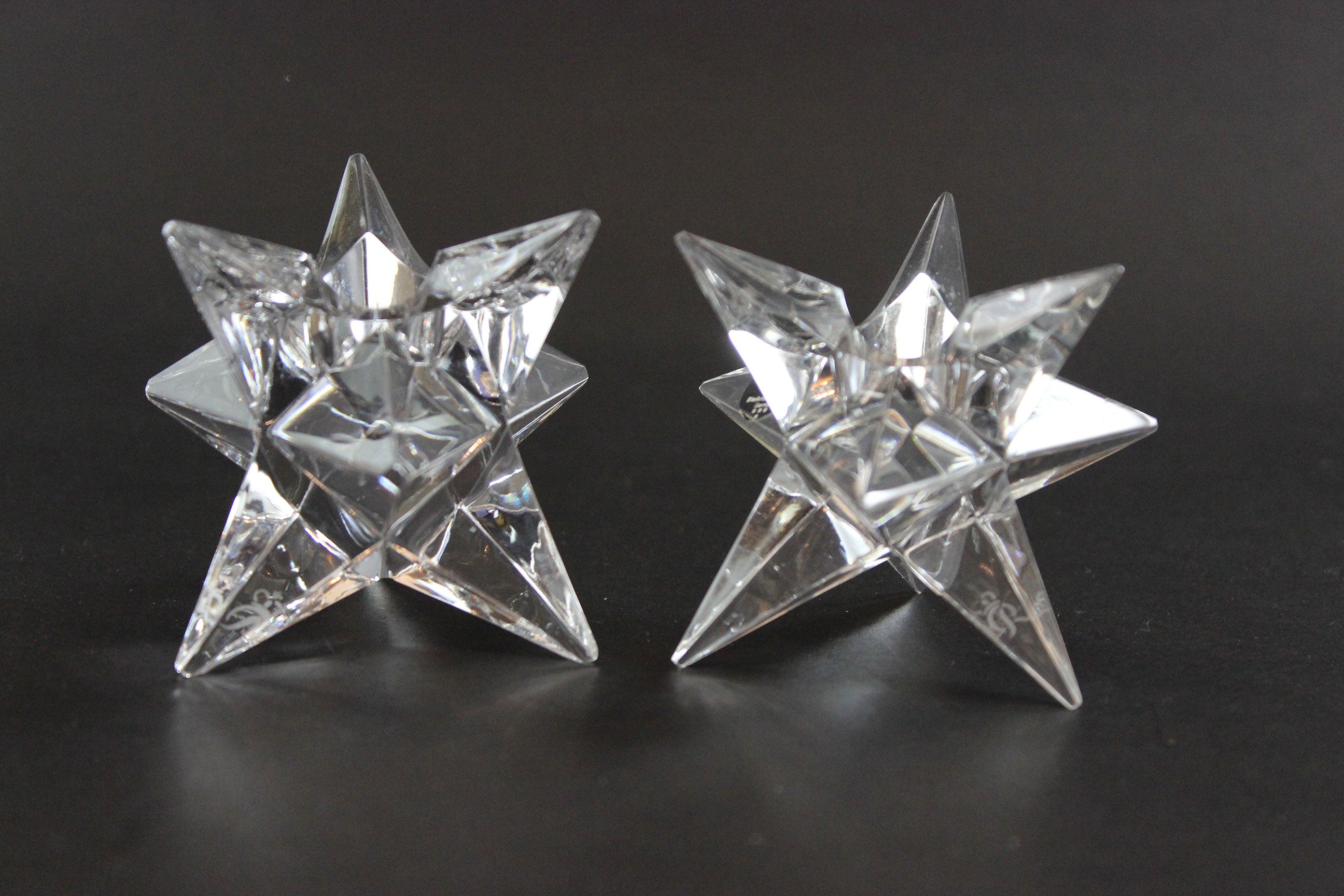 Set of crystal star-shaped candleholders on a dark background