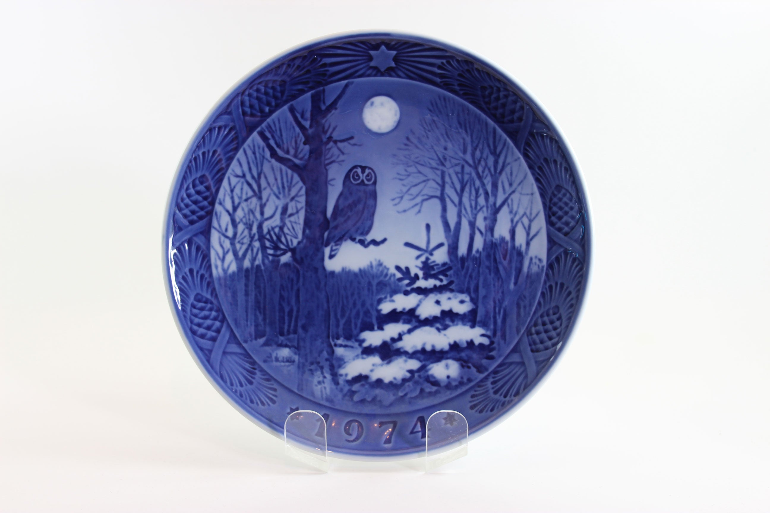 1974 Royal Copenhagen Blue ceramic plate with winter scene and owl, on a white background.