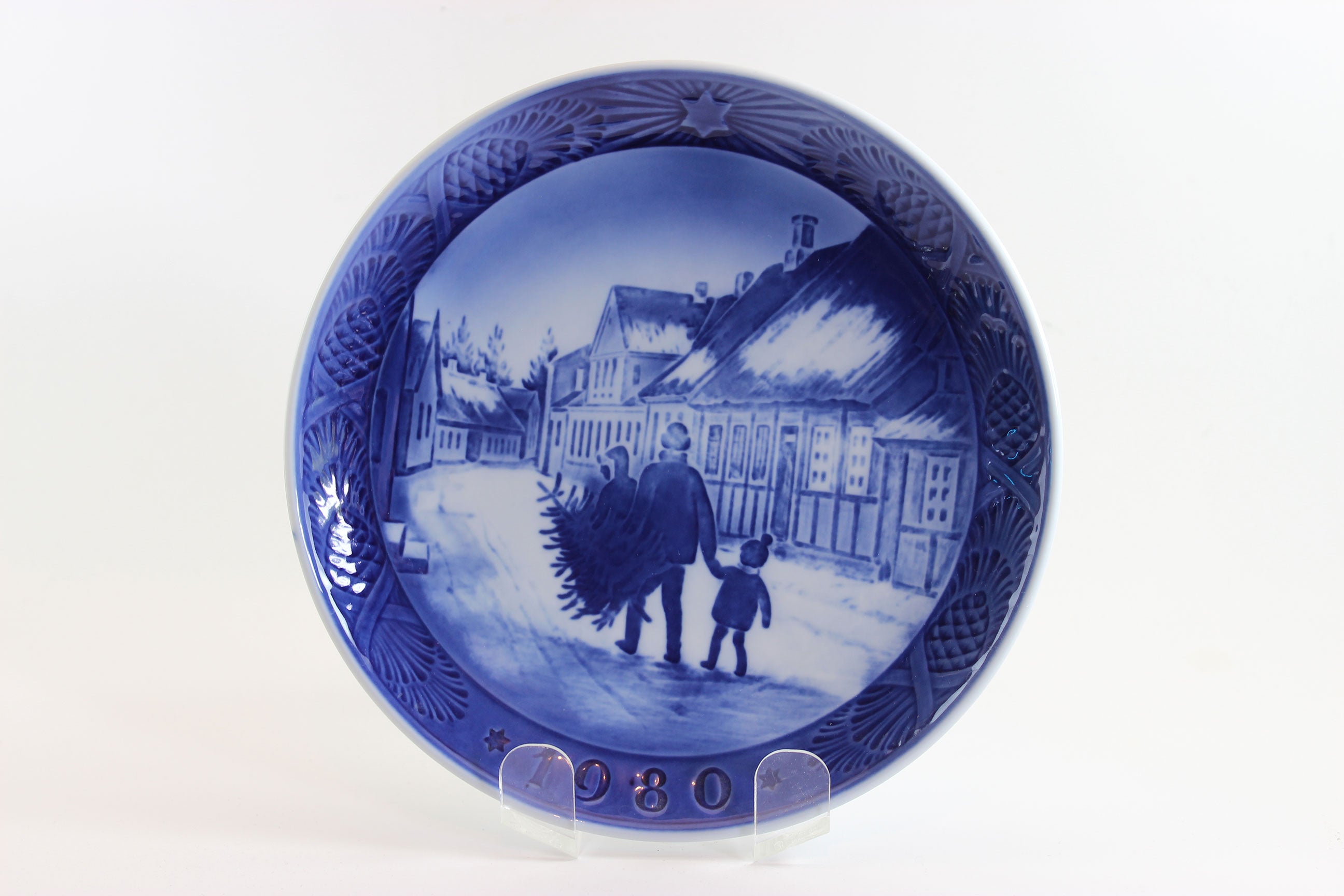Annual blue and white Christmas plate 1980 with a scene of a man and child walking, on a white background.