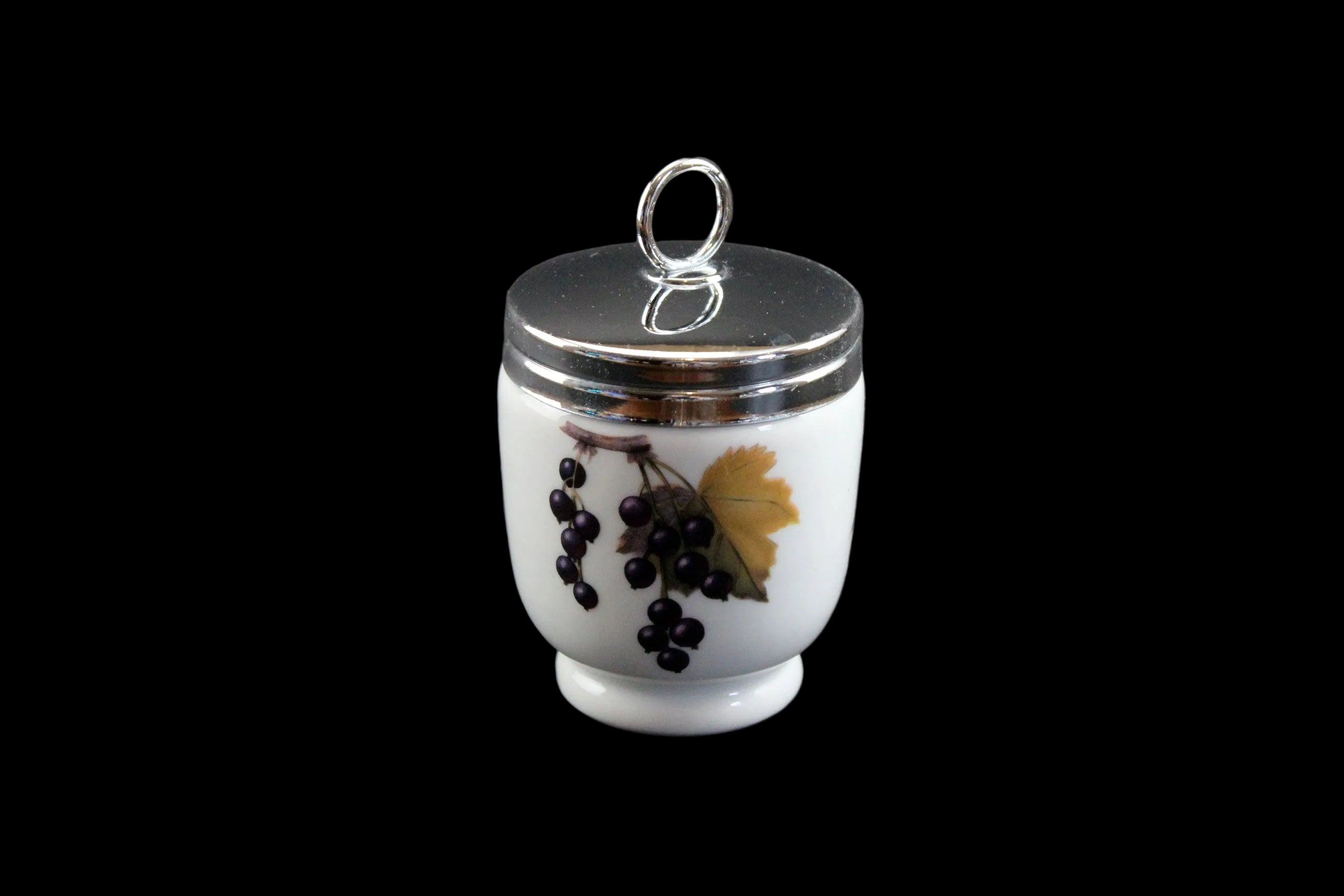 Small white egg coddler r with silver lid and black grapes design on a dark gray background