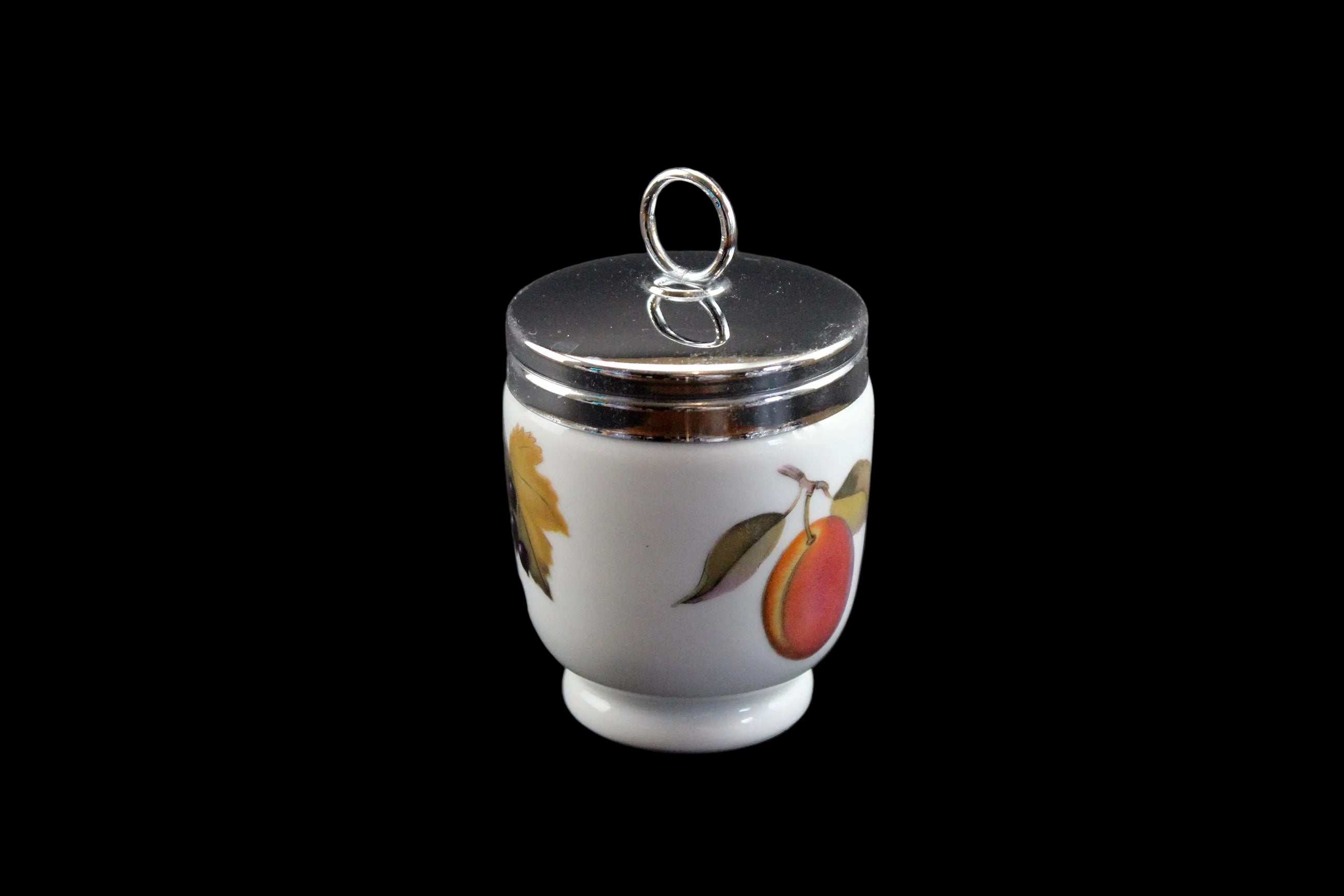 Small ceramic jar with a silver lid on a dark background