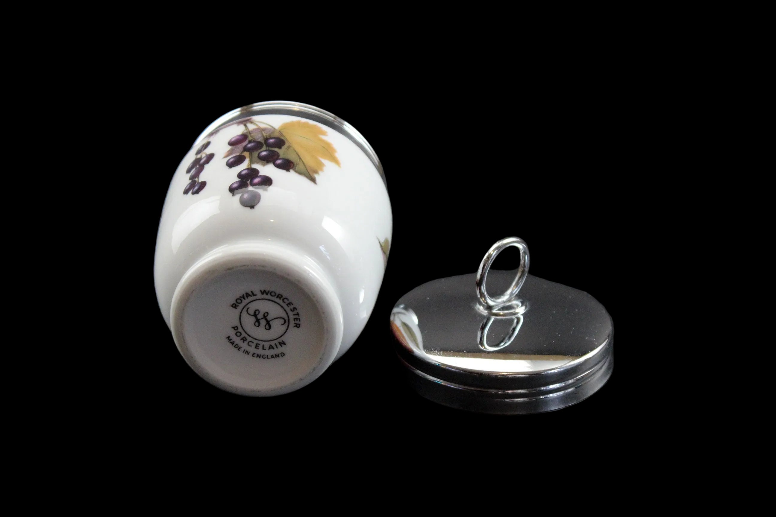 Small ceramic container with lid featuring a fruit design on a dark background
