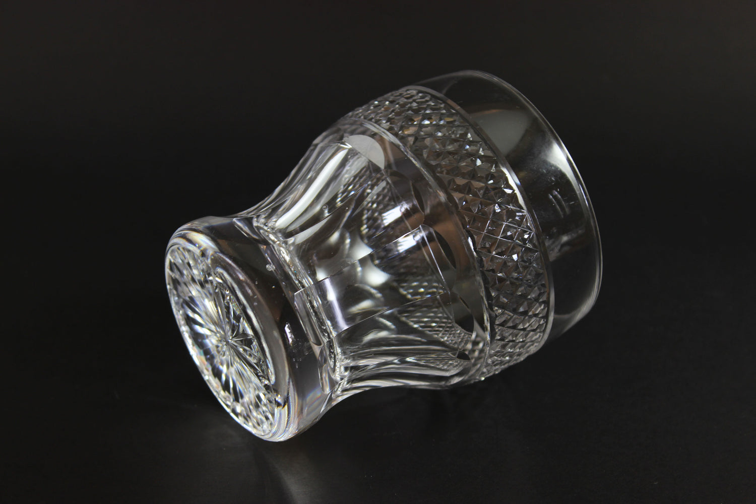 Clear crystal whiskey tumbler with intricate design on a black background