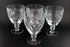 Four crystal glasses with cut patterns on a black background