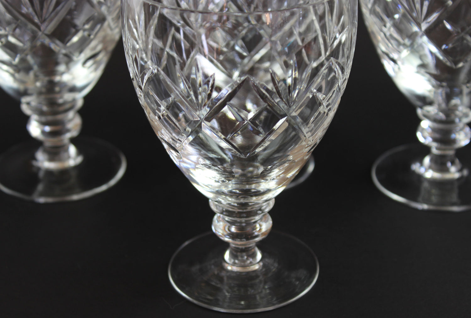 Close-up of crystal glasses with intricate cut patterns on a black background
