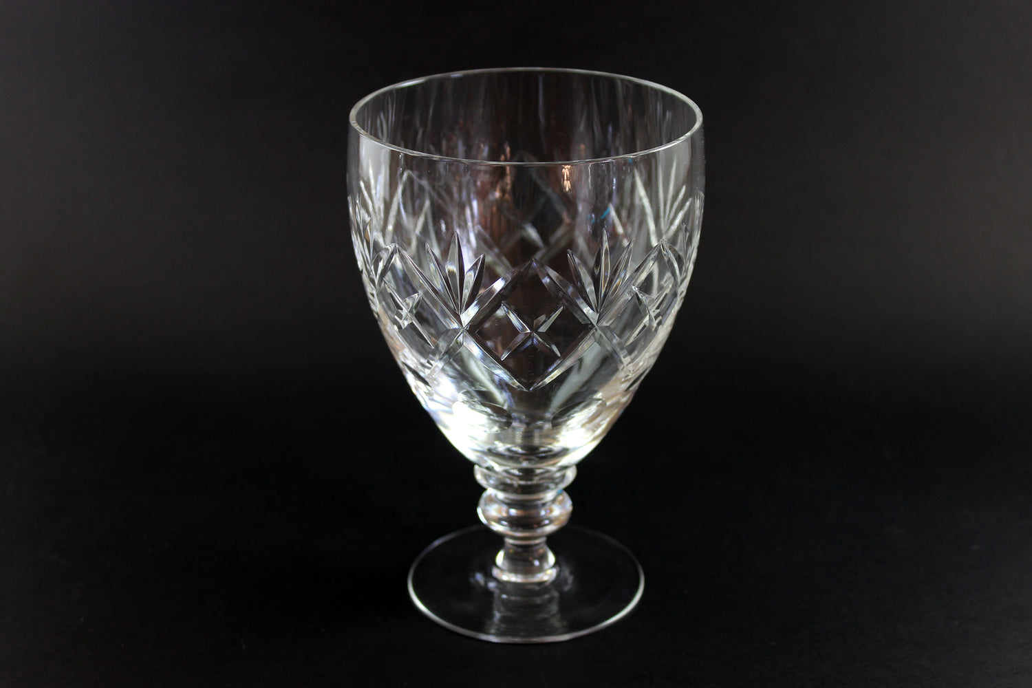 Clear glass goblet with diamond cut pattern on a black background