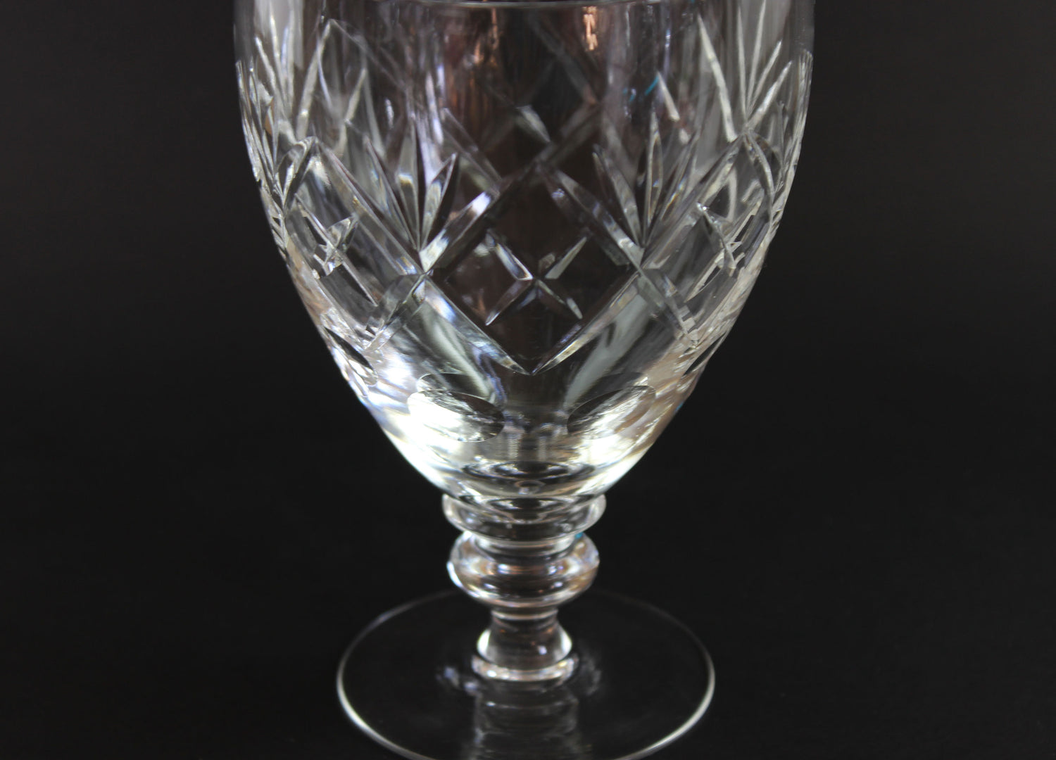 Crystal glass goblet with intricate cut patterns on a black background