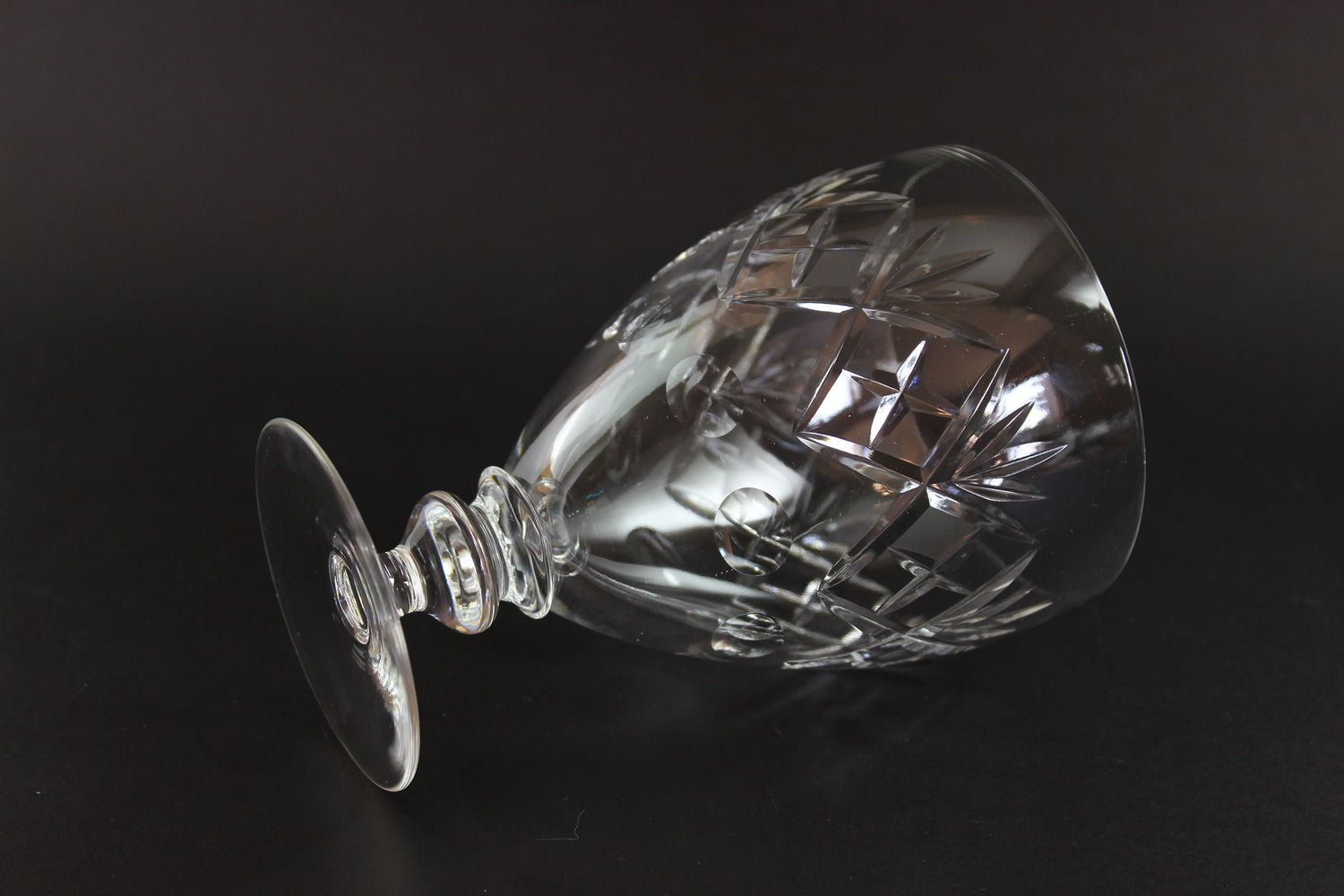 Clear glass goblet with intricate cut patterns on a black background