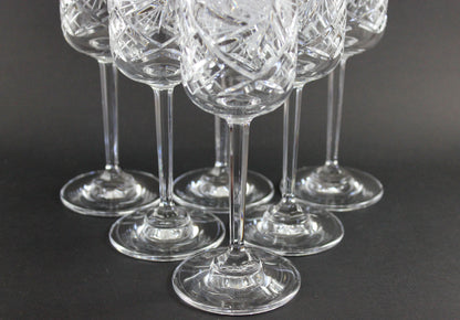 Set of six crystal champagne flutes with cut designs on a black background