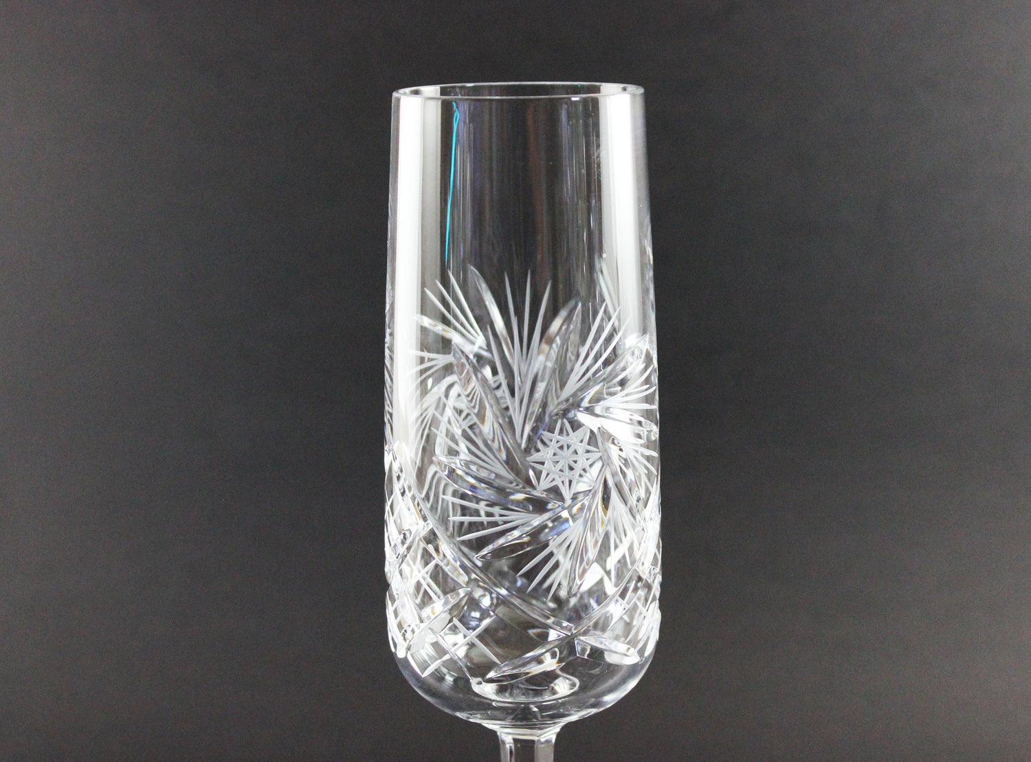 Crystal champagne flute with intricate cut design on a dark background