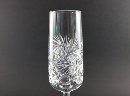 Crystal champagne flute with intricate cut design on a dark background