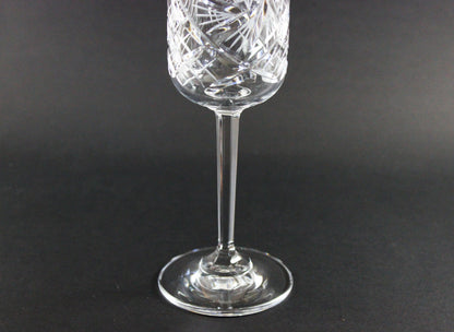 Crystal wine glass with intricate cut design on a black background