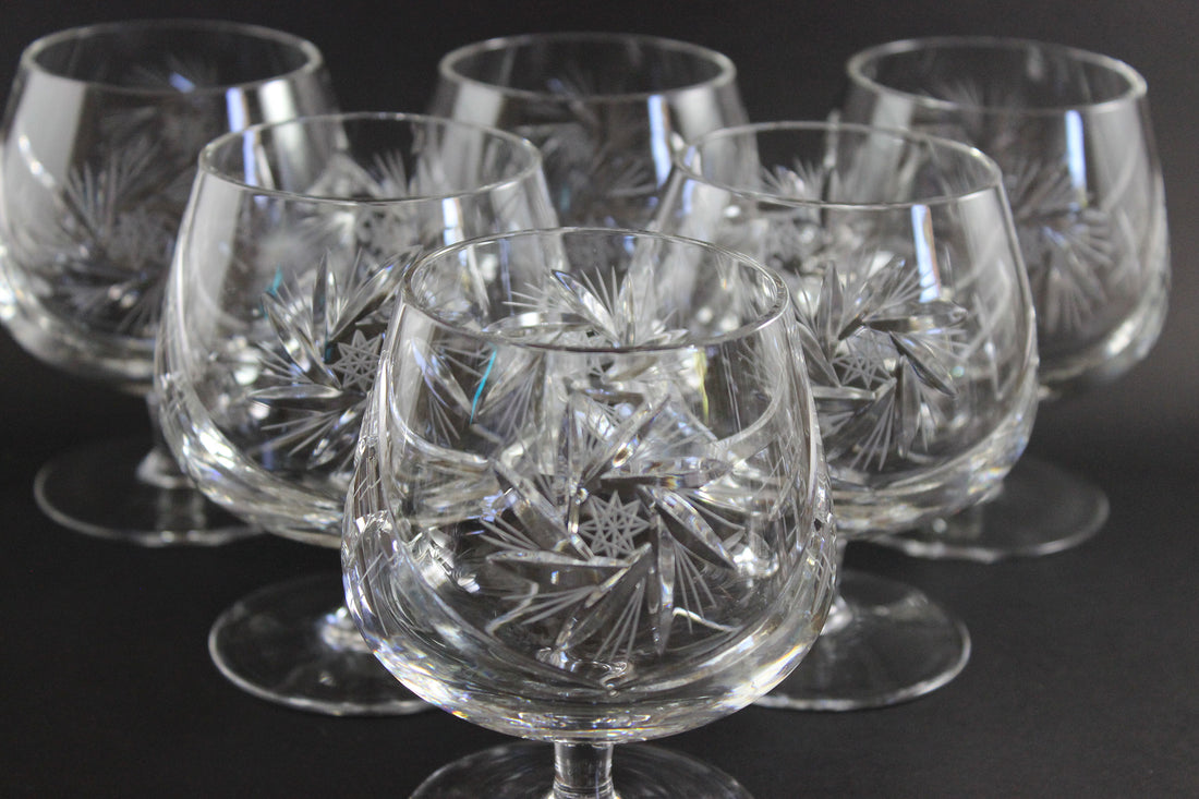 Set of crystal glasses with intricate designs on a dark background