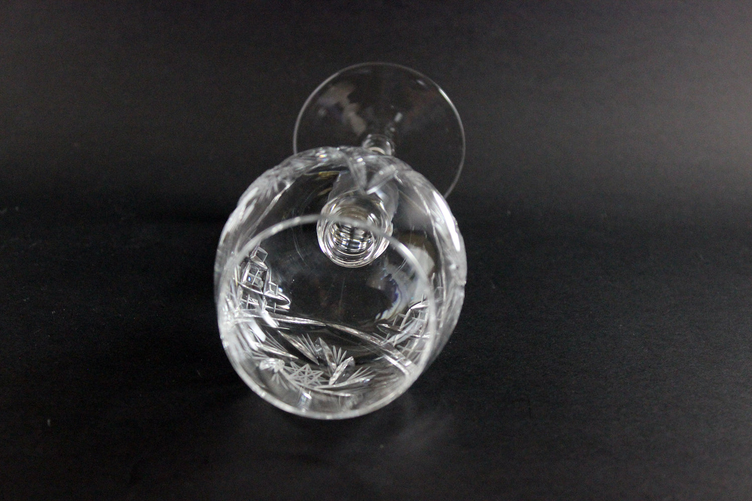 Clear crystal wine goblet with cut design on a black background