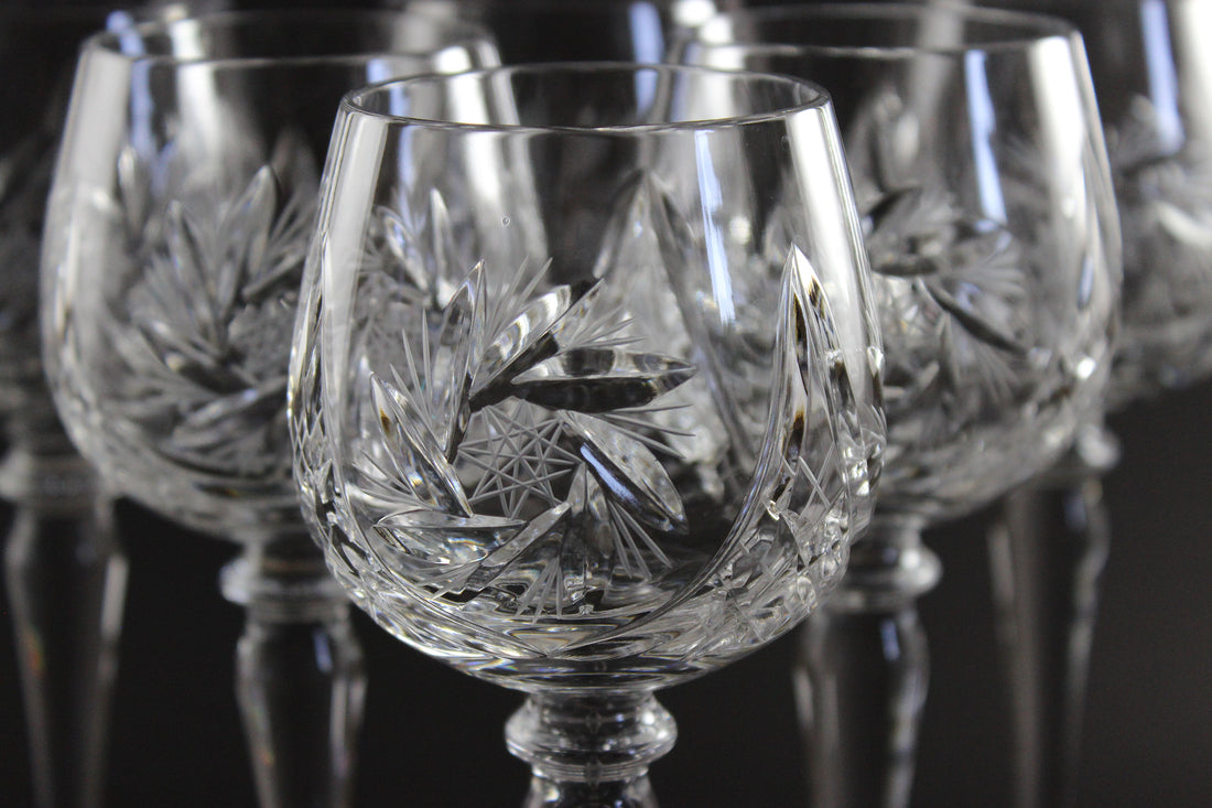 Set of crystal glasses with intricate cut patterns on a dark background