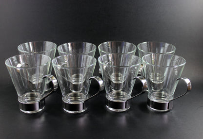 Set of clear glass tumblers with metal bases on a black background