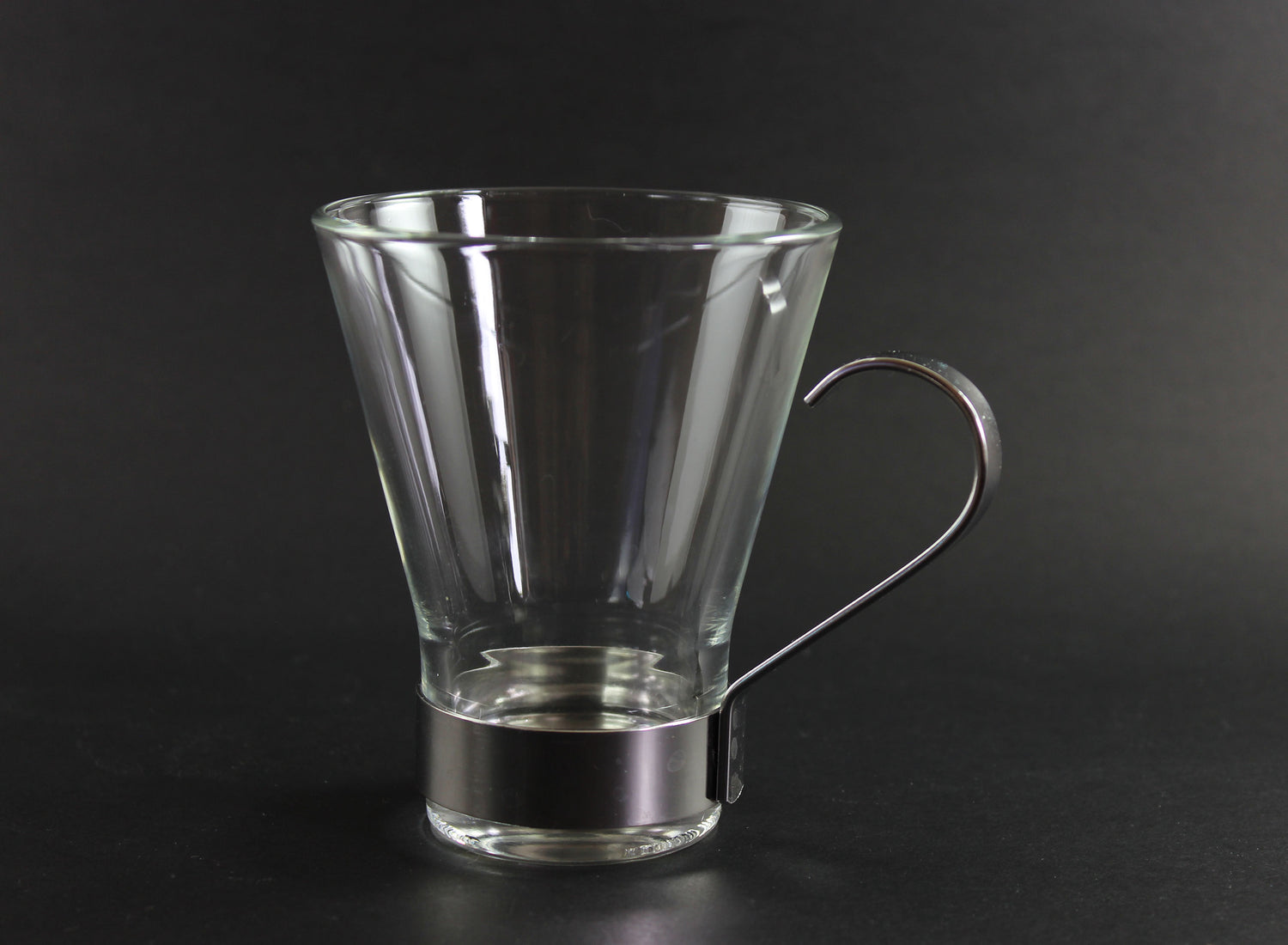 Clear glass mug with metal handle on a black background