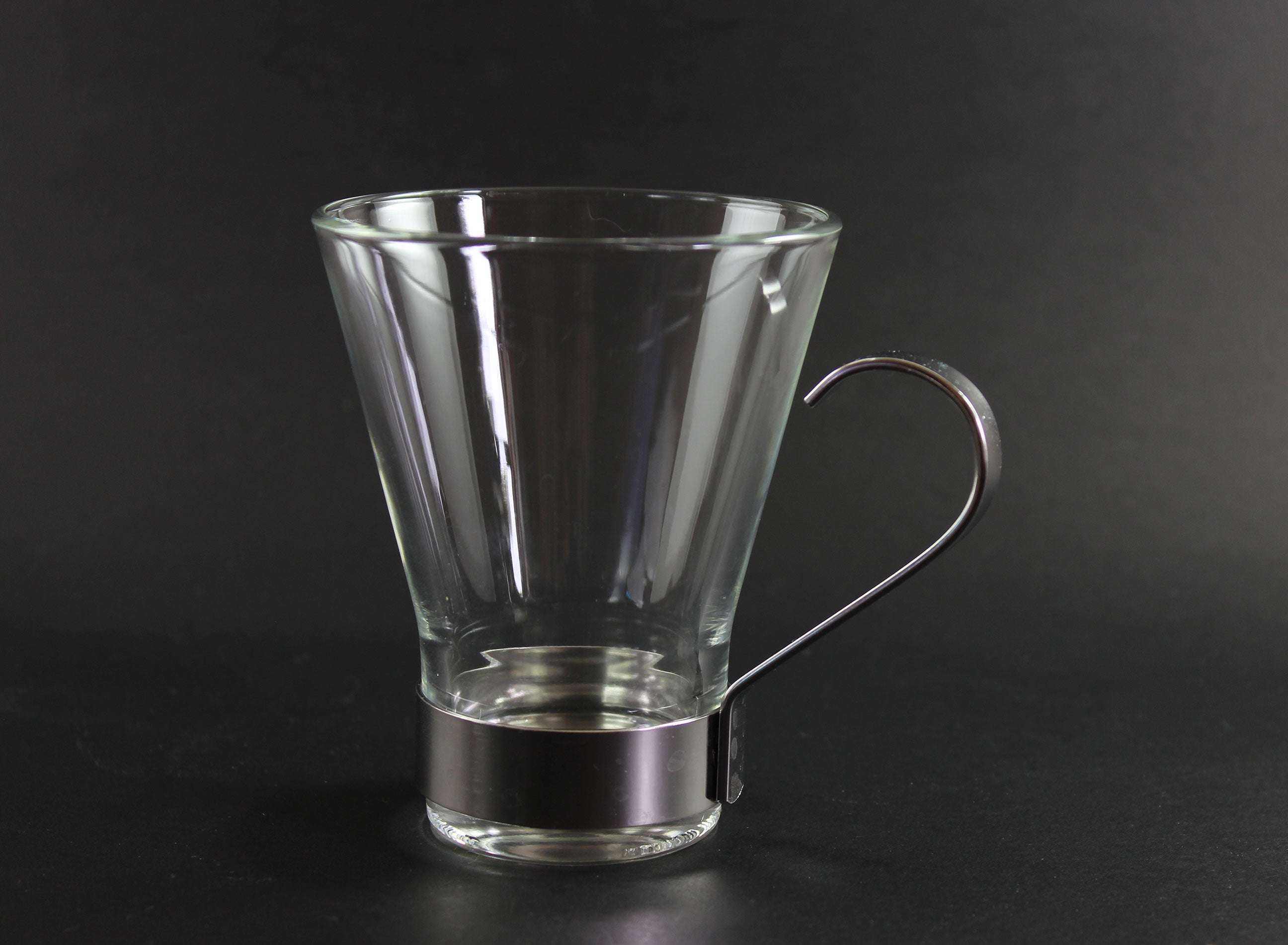 Clear glass mug with metal handle on a black background