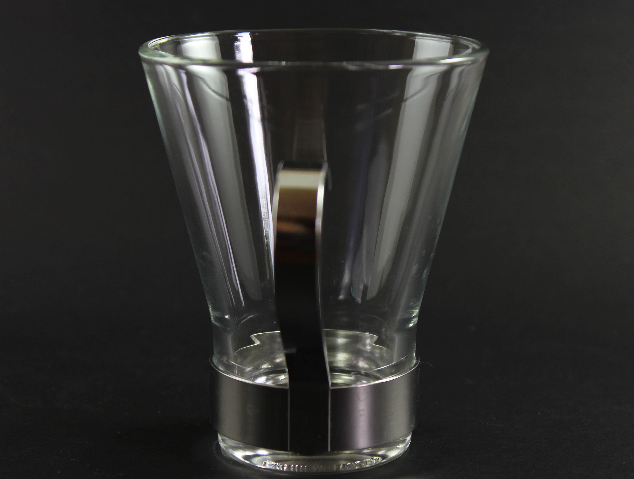 Clear glass mug with metal handle on a black background
