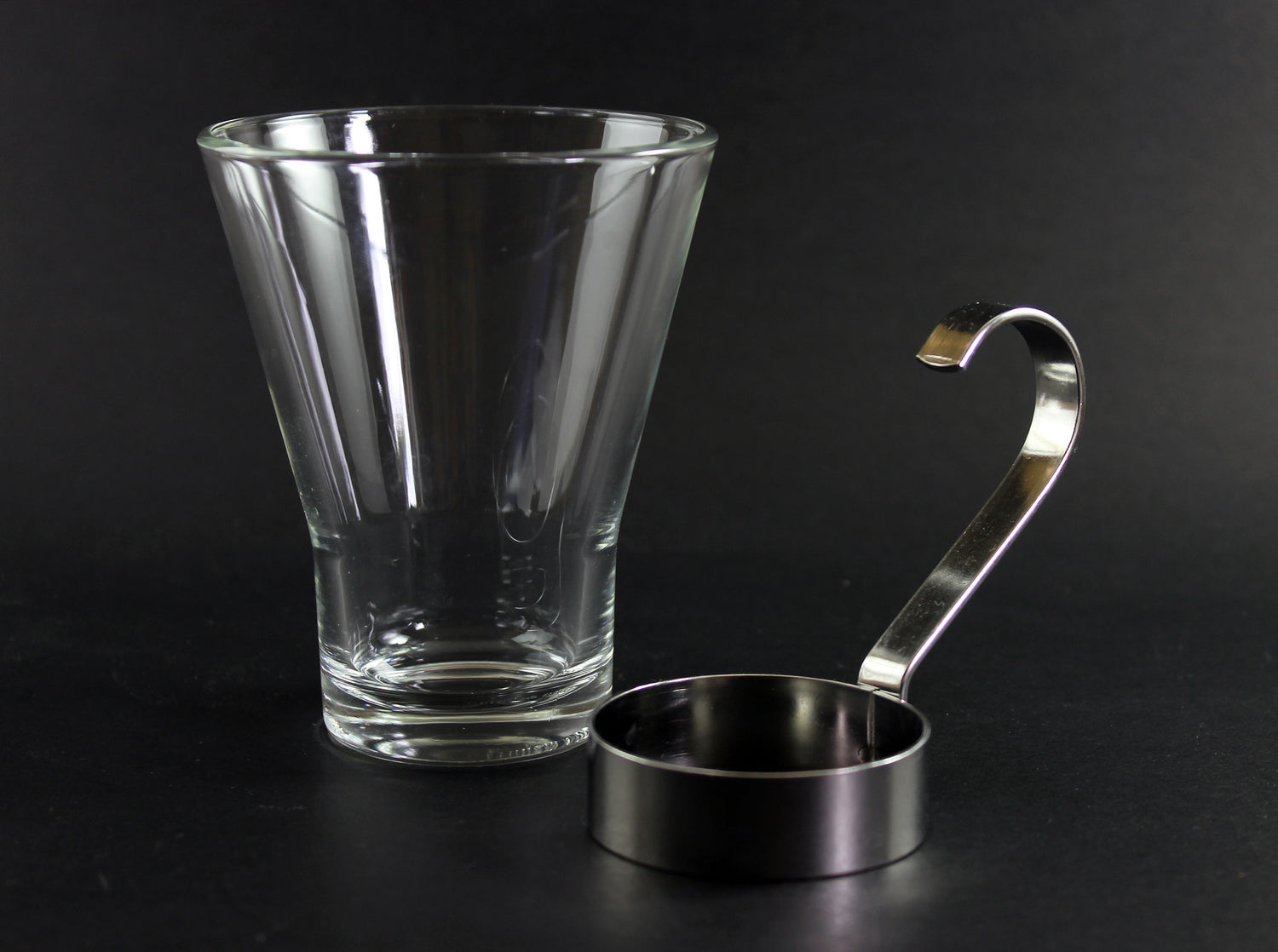 Clear glass mug with metal handle on a black background