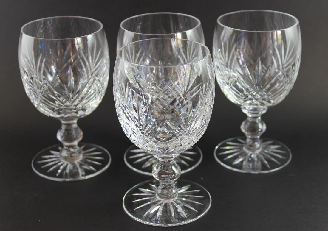 Set of four crystal glasses with cut patterns on a dark background