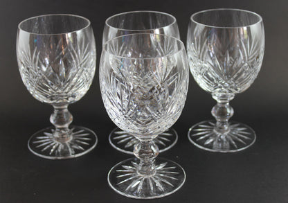 Set of four crystal glasses with cut patterns on a dark background