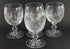 Set of four crystal glasses with cut patterns on a dark background