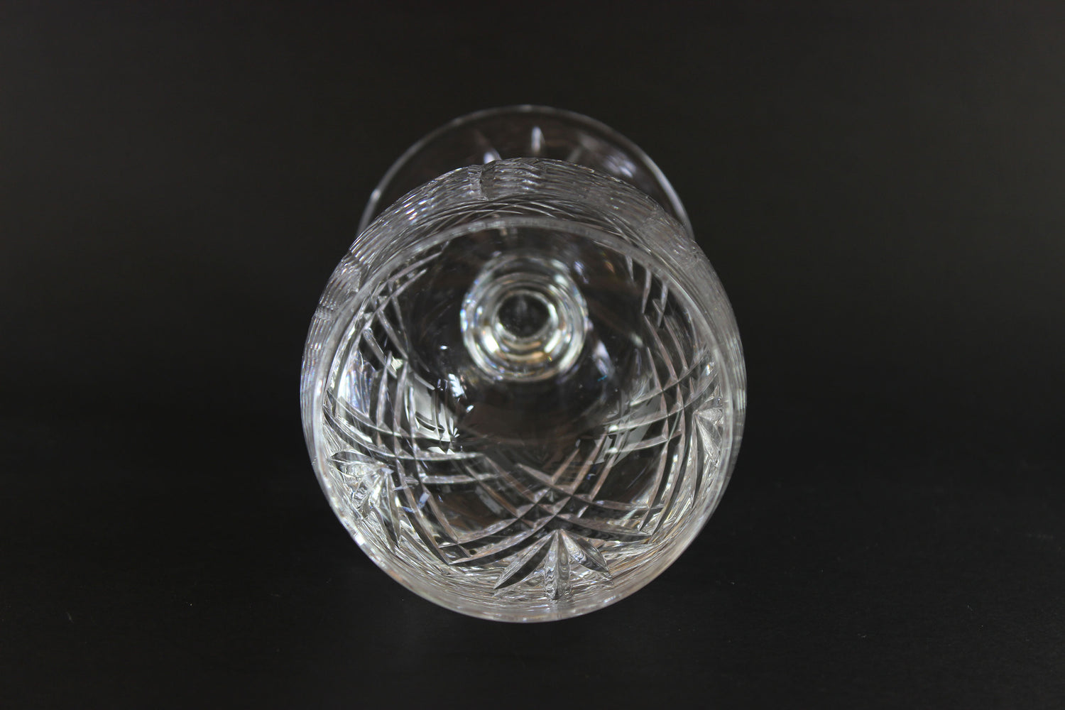 Cut crystal wine glass with intricate cut patterns on a black background