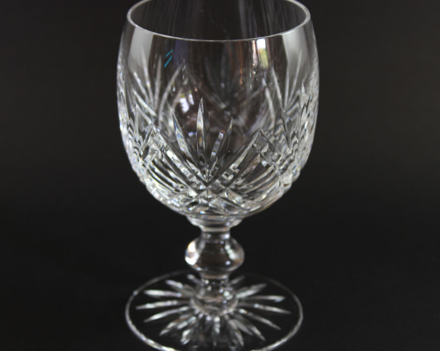 Crystal wine glass with intricate cut patterns on a black background
