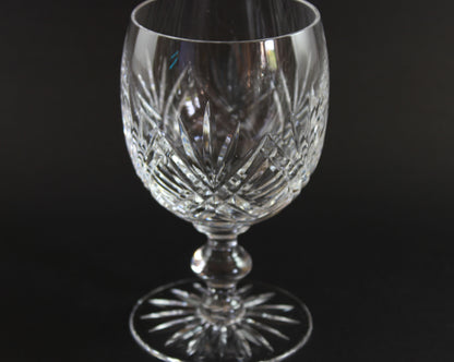 Crystal wine glass with intricate cut patterns on a black background