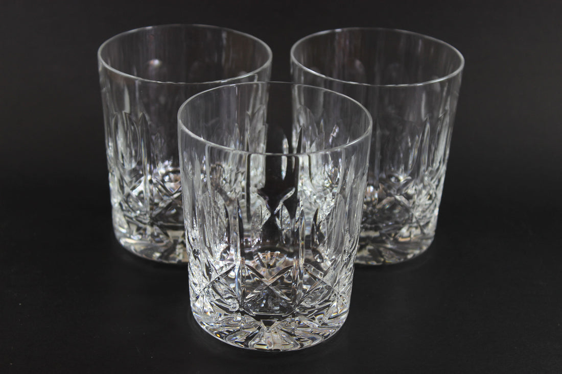Three crystal glasses with cut patterns on a black background