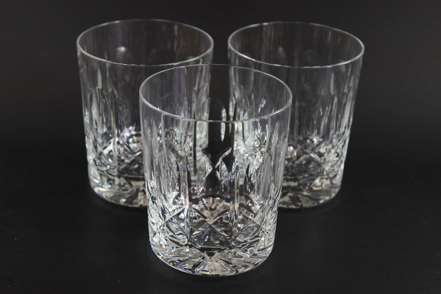 Three crystal glasses with cut patterns on a black background