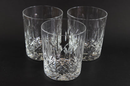 Three crystal glasses with cut patterns on a black background