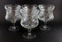 Four clear glass goblets with textured design on a black background