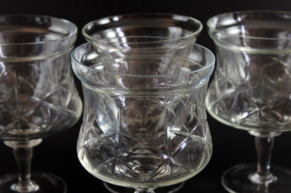 Set of clear glass tumblers with cross and olive cut pattern on a dark background