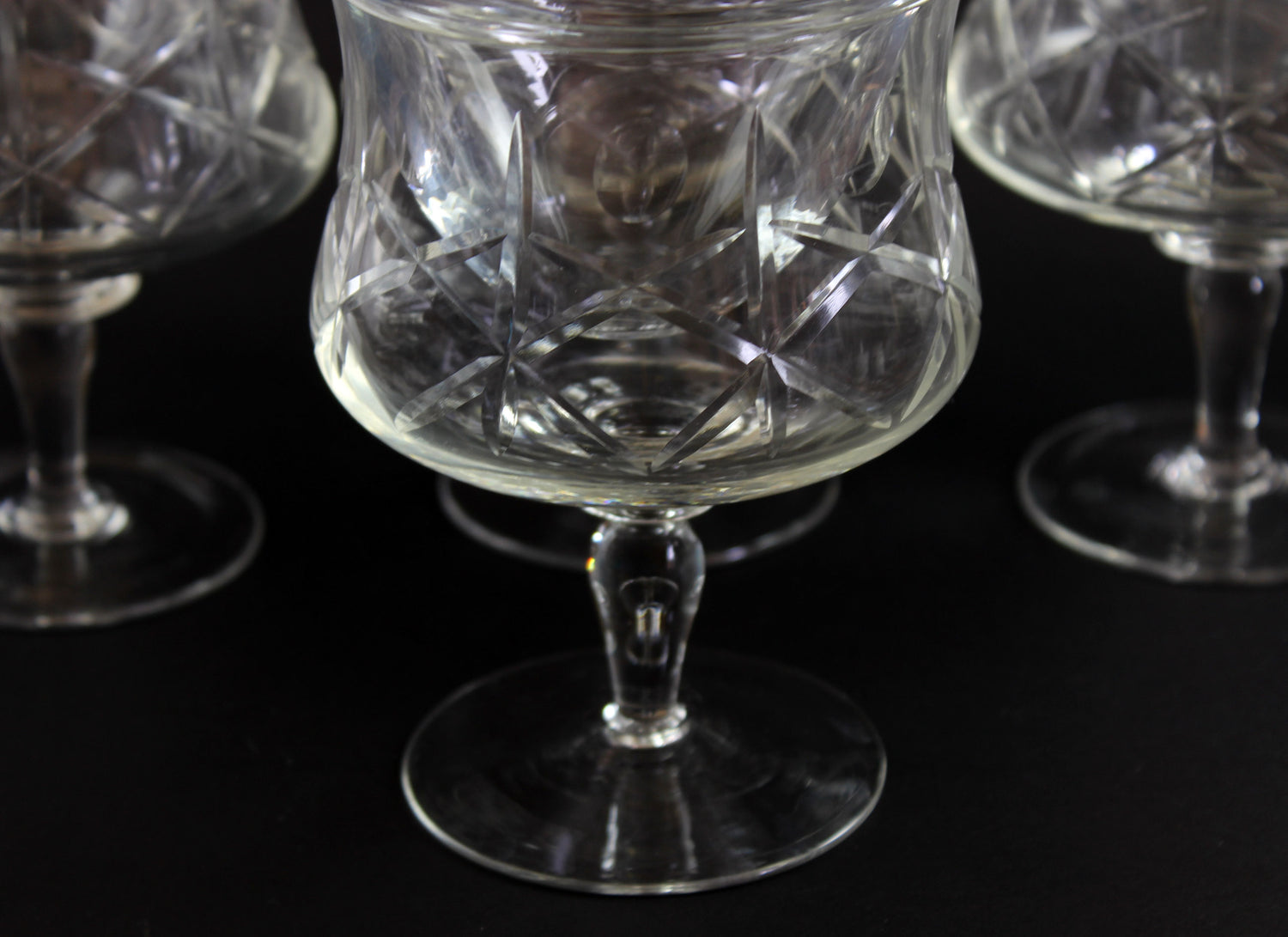 Set of crystal glasses with intricate cut patterns on a black background