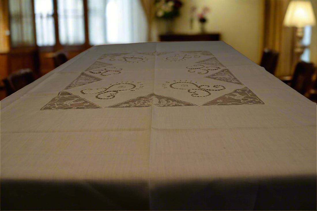 Tablecloth with decorative patterns on a table in a room with chairs and a lamp.