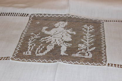 Embroidered design on a white fabric with a person and trees.