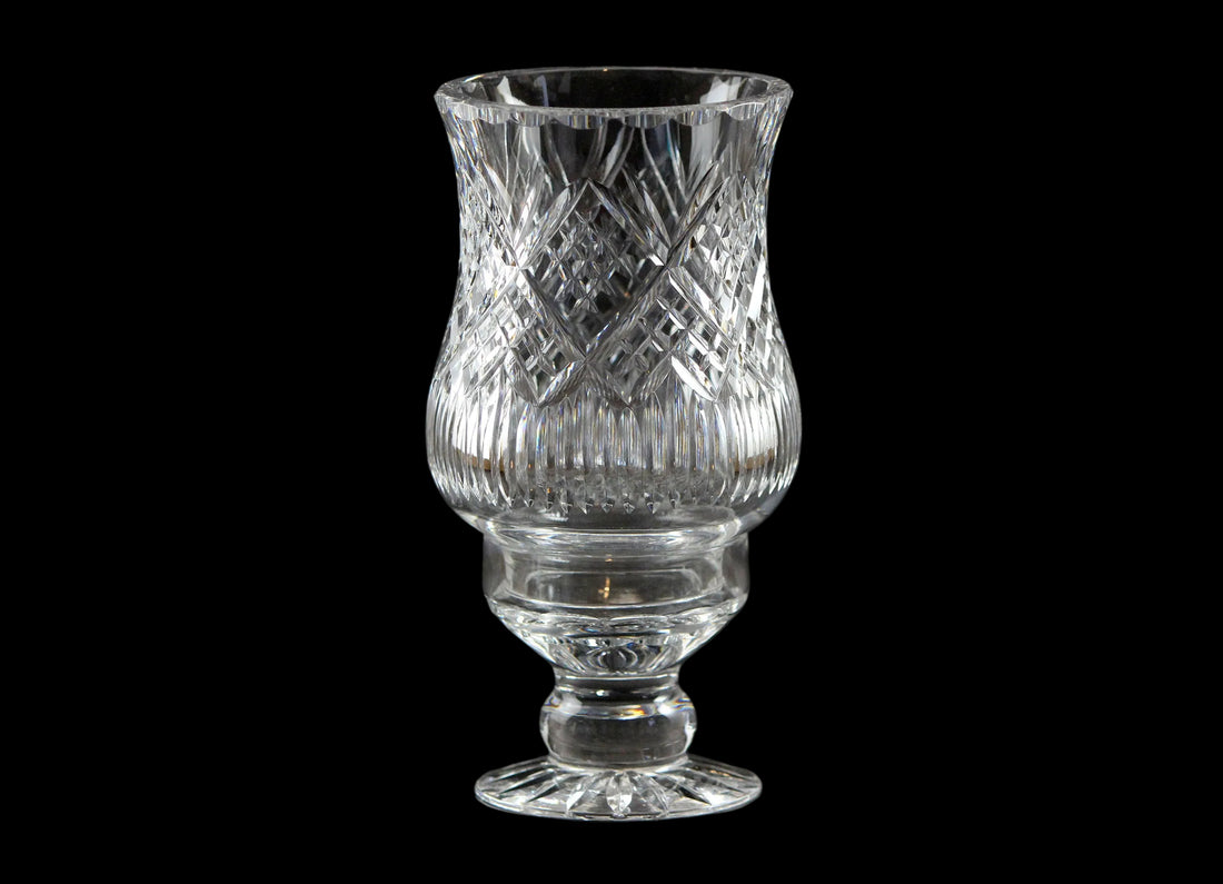 Clear glass hurricane lamp with intricate design on a black background