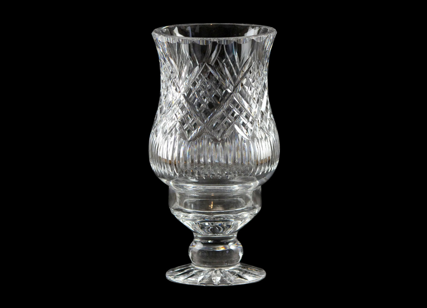 Clear glass hurricane lamp with intricate design on a black background