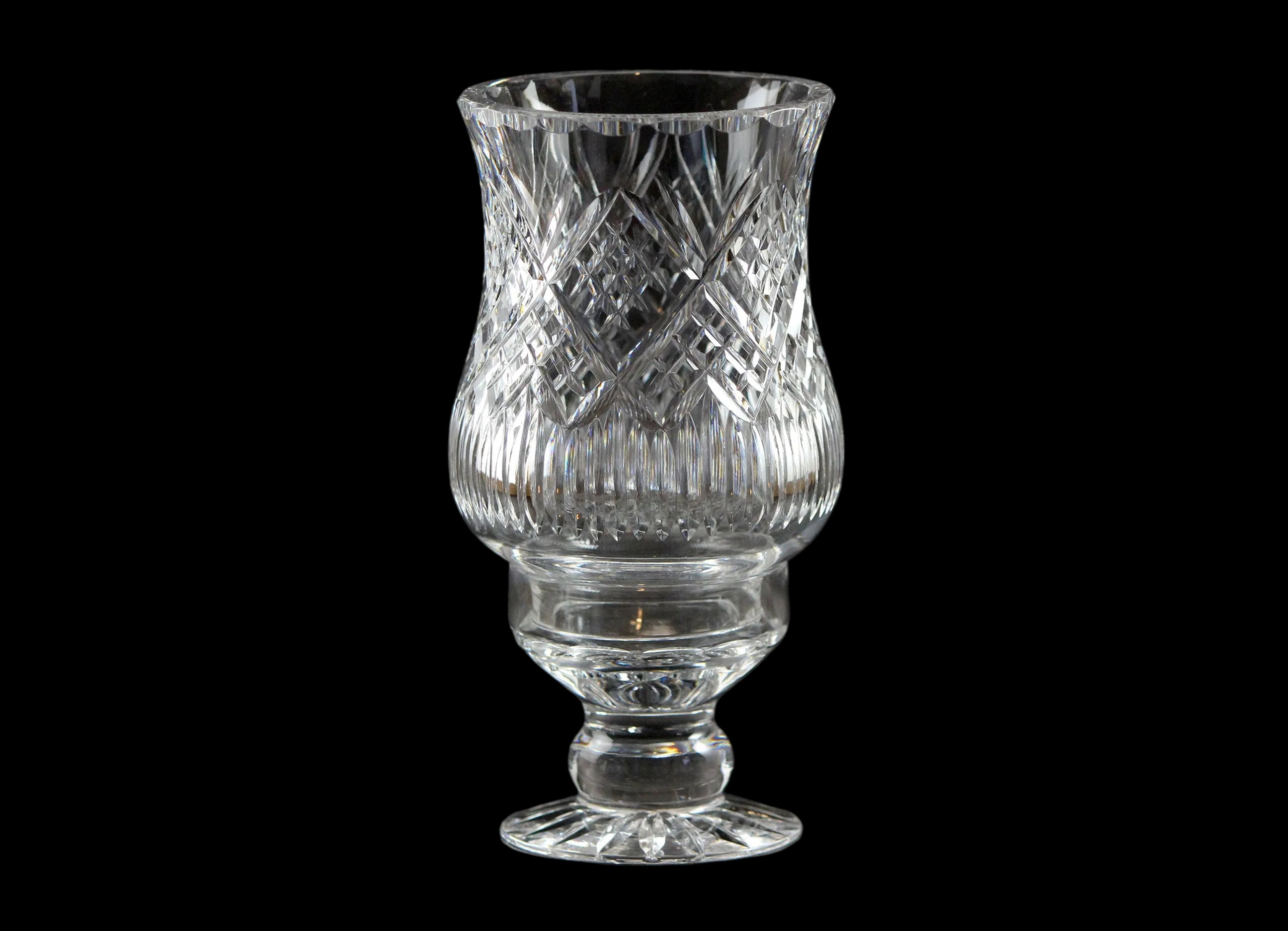 Clear glass hurricane lamp with intricate design on a black background