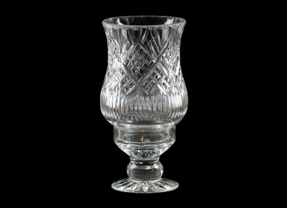 Clear glass hurricane lamp with intricate design on a black background