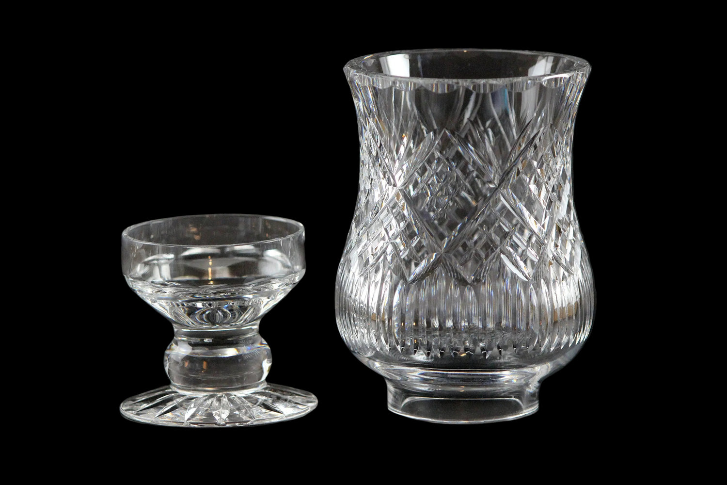 Clear glass hurricane lamp with intricate cut patterns on a black background