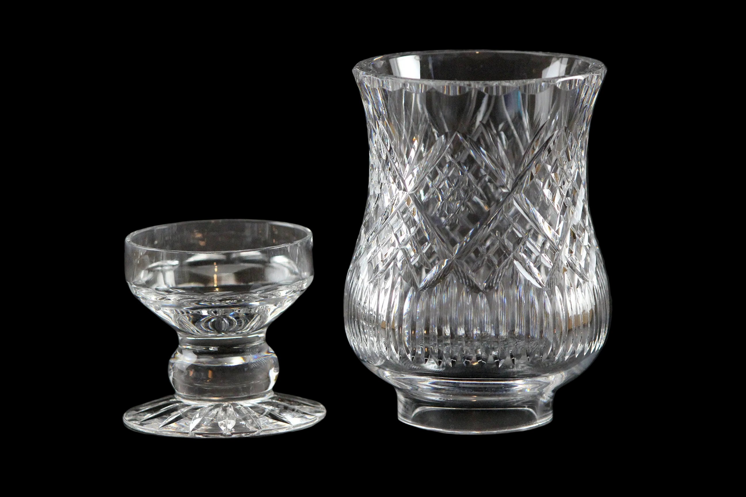 Clear glass hurricane lamp with intricate cut patterns on a black background